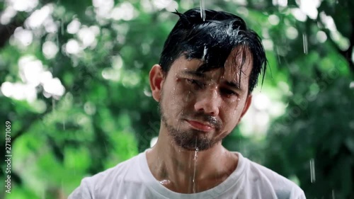 Young man Unhappy standing in the rain, Portrait of a sad man in the rain,  Bad stormy rainy weather concept