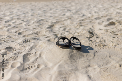 Summer holiday concept. Black pair of sandals on beach.