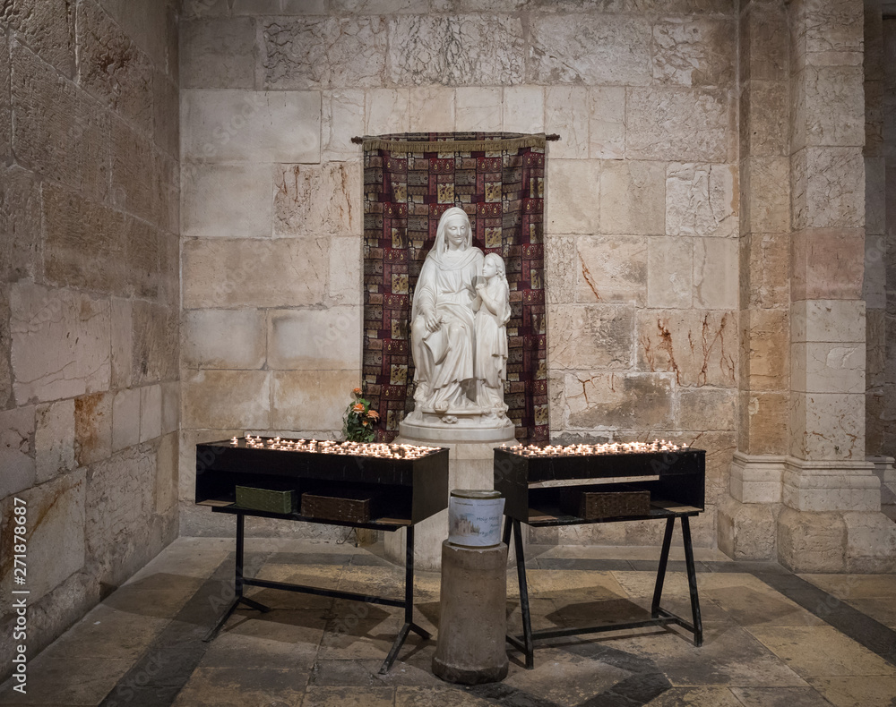 Tables with candles stand in front of the statue in the Church of Saint