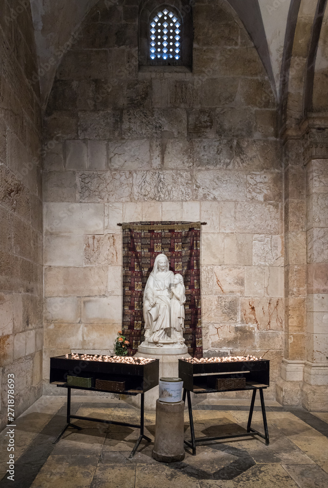 Tables with candles stand in front of the statue in the Church of Saint