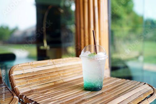 A plastic glass of Iced mojito soda with mint on blurred background, Summer Cocktail or Tropical Mocktail.