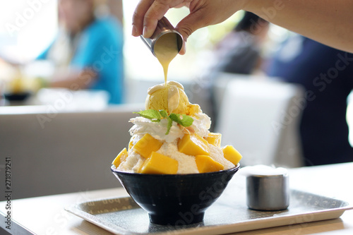 Фотография Mango Bingsu (Kakigori) - Korean shaved ice dessert flavor, stuffed with sticky rice, topped with whipped cream and mango ice cream, served with condensed milk, Traditional summer dessert in Korea