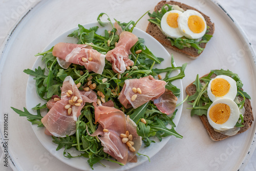 Healthy salad with prosciutto, tomato and green leaves
