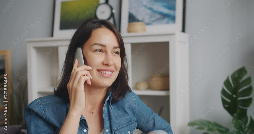 Happy young lady student is talking on mobile phone holding smartphone in apartment. Modern communication, cheerful millennials and leisure time concept. Happy young lady student is talking on mobile phone holding smartphone in apartment. Modern communication, cheerful millennials and leisure time concept.