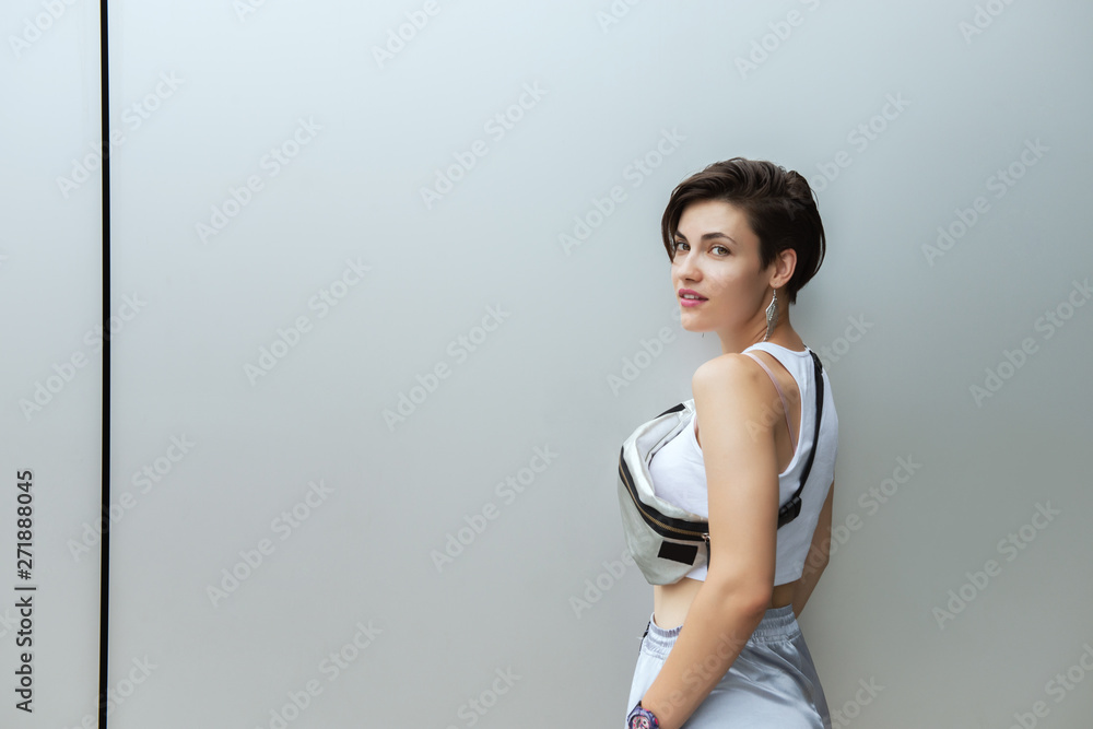 Young attractive woman posing outdoor over silver metal background 