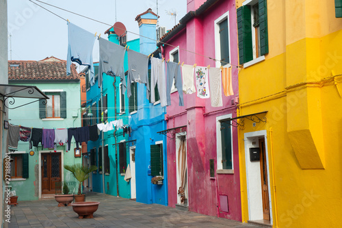 Colorful houses on the Italian island Burano, province of Venice, Italy. Multicolored buildings in fog, Italian courtyard with dry laundry outdoor.