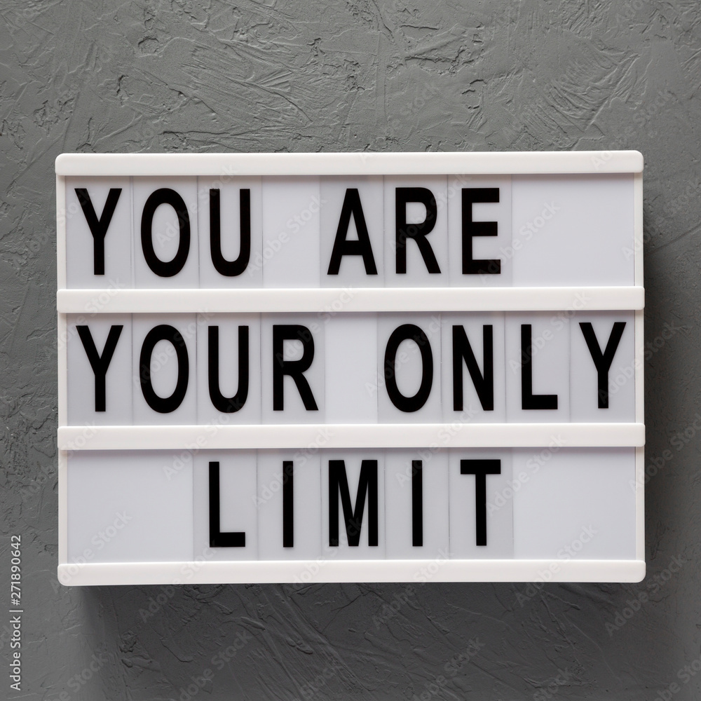 Fototapeta premium 'You are your only limit' words on a light box over gray background, top view. Overhead, from above. Flat lay.