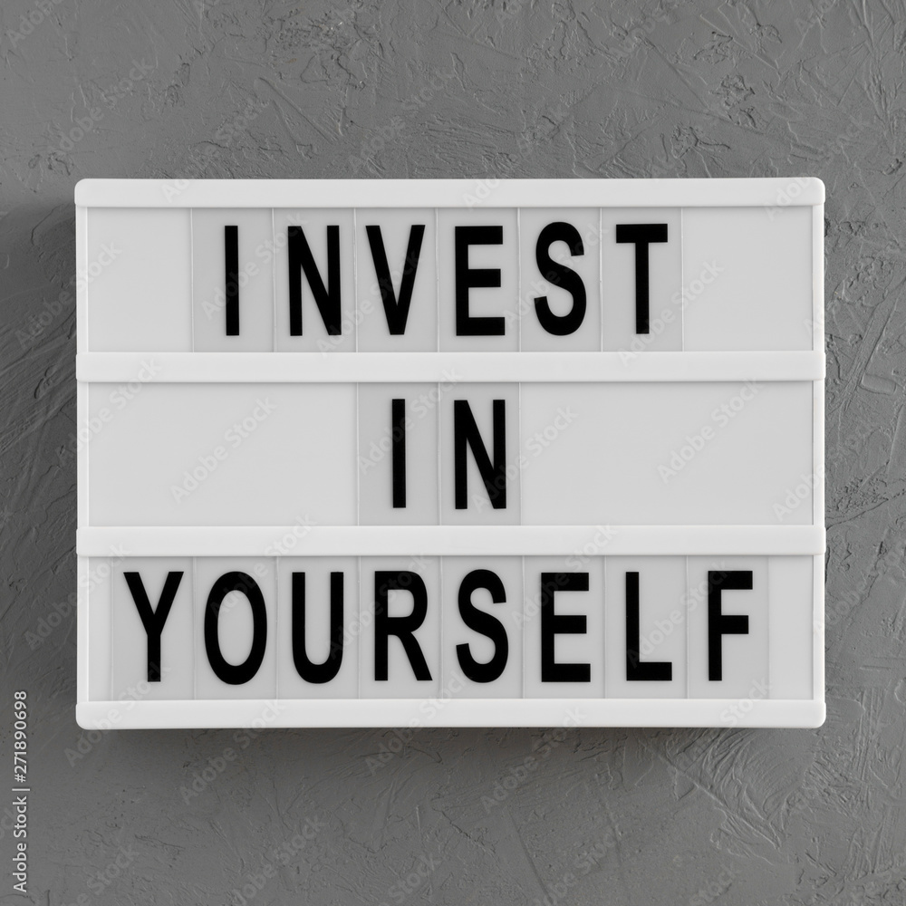 'Invest in yourself' words on a light box on a concrete surface, overhead view. Flat lay, from above, top view. 'Invest in yourself' words on a light box on a concrete surface, overhead view. Flat lay, from above, top view.
