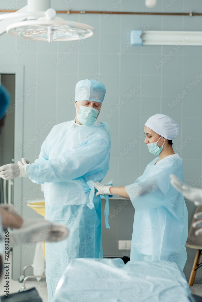 senior doctor ties belt around the doctor's waist. close up side view photo. senior doctor ties belt around the doctor's waist. close up side view photo.