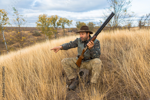 Hunter with a hat and a gun in search of prey in the steppe 