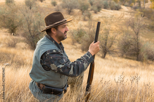 Hunter with a hat and a gun in search of prey in the steppe 