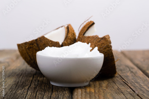 pile of rigid coconut oil on china dish and broken coconut shells, old wood table