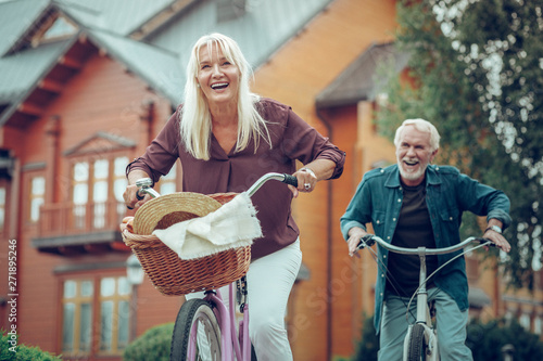 Obraz na plátně Joyful happy aged couple riding bikes together