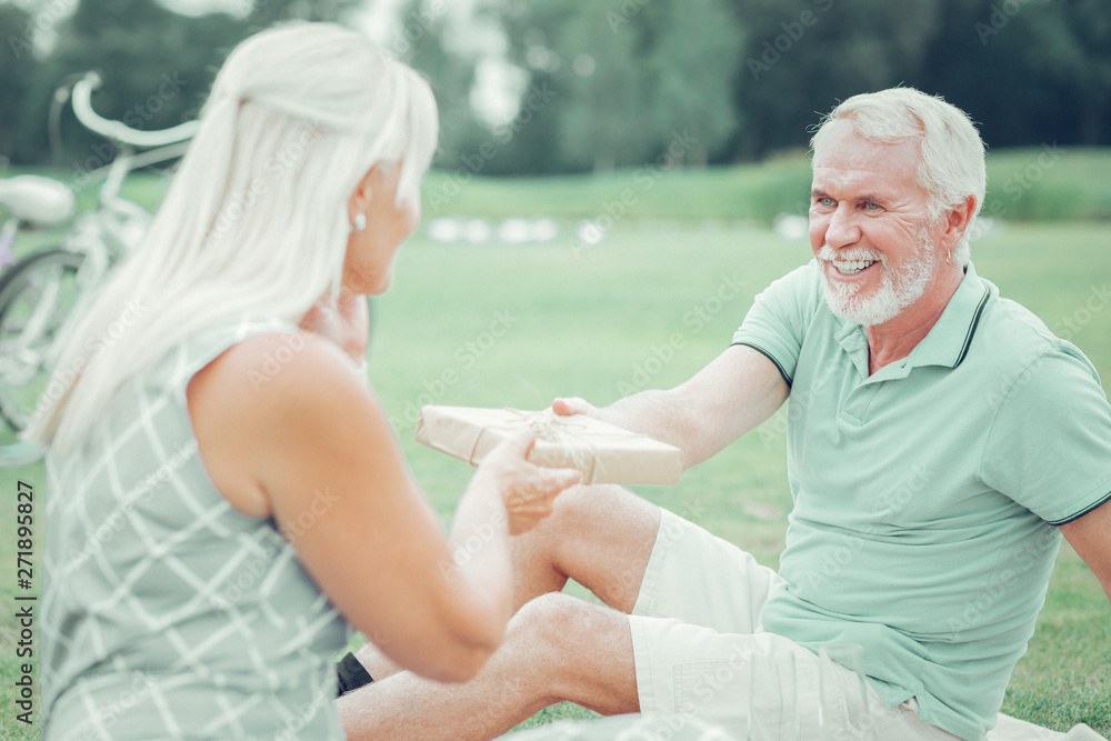 Joyful bearded man giving a present to his wife Joyful bearded man giving a present to his wife