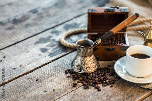 coffee cup, metal turk and coffee beans on a wooden background
