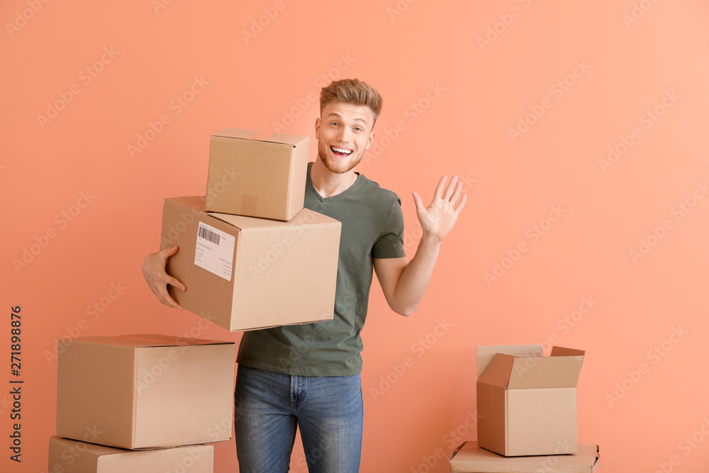 Young man with cardboard boxes on color background Young man with cardboard boxes on color background