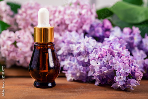 lilac essential oil bottle with blooming lilac branch