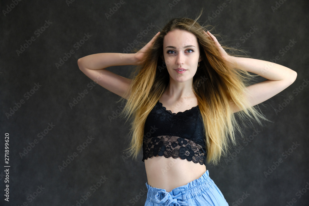 Photograph of a portrait of a beautiful girl woman with long dark flowing hair, happy life on a dark gray background. She is standing directly in front of the camera in various poses and smiling.