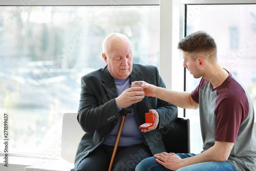 Male caregiver giving pills...