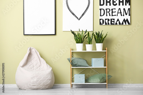 Tableau sur toile Comfortable beanbag and shelf unit near color wall