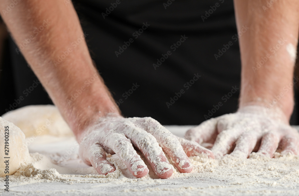 Man with hands in flour on dark background, closeup