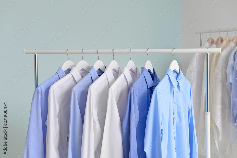 Rack with clothes after dry-cleaning on light background Stock Photo