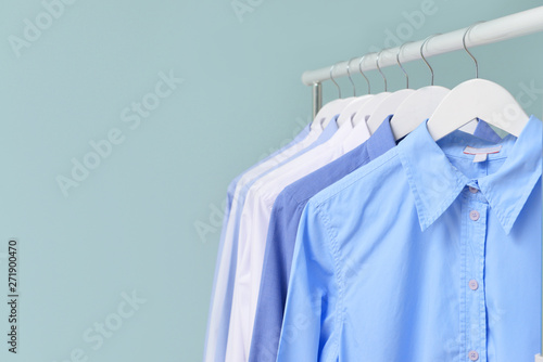 Rack with clothes after dry-cleaning on light background
