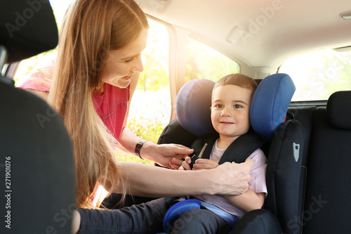 Mother buckling her little son in car seat © Pixel-Shot
