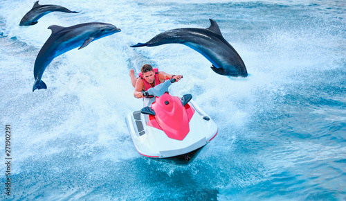 Man on jet ski jump on the wave with Jumping dolphin in the sea photo