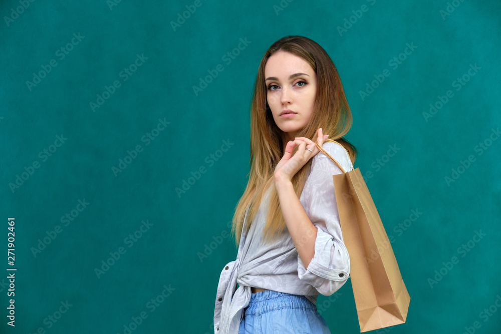 Photograph of a portrait of a beautiful girl woman with long dark flowing hair, loves shopping, on a green background with packages from the store. She is standing in different poses and smiling. Photograph of a portrait of a beautiful girl woman with long dark flowing hair, loves shopping, on a green background with packages from the store. She is standing in different poses and smiling.