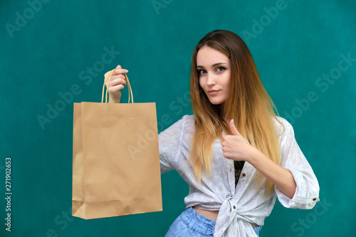Photograph of a portrait of a beautiful girl woman with long dark flowing hair, loves shopping, on a green background with packages from the store. She is standing in different poses and smiling.