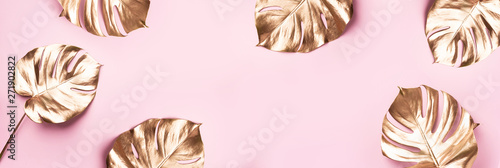 Exotic summer trend in minimal style. Golden tropical palm monstera leaf on pastel pink color background. Shiny and sparkle design, fashion concept.