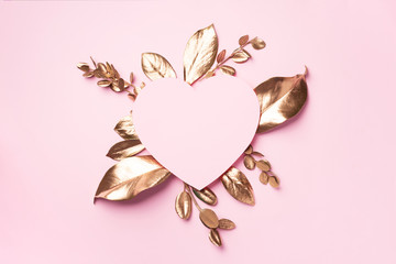 Golden leaves, heart shaped paper on pink background with copy space. Top view. Copy space. Summer and autumn concept. Creative design elements