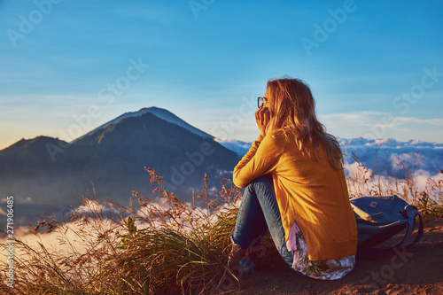 Woman enjoying nice landscape and sunrise from a top of mountain Batur, Bali, Indonesia. photo