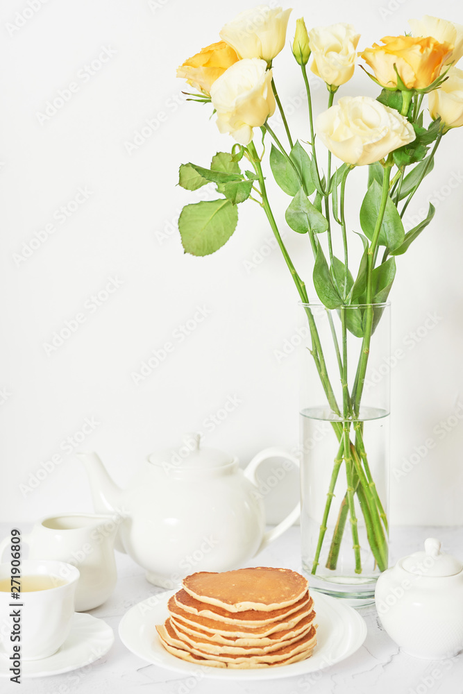 Independence Day on July 4th, American pancakes on the table next to the crockery and yellow flowers in the vase.