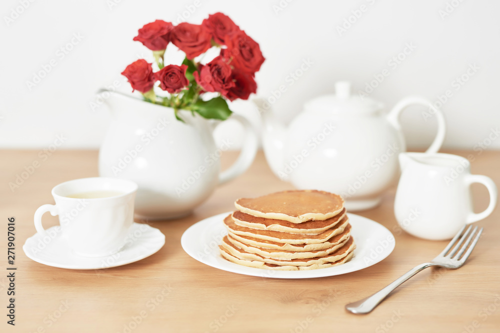 Independence Day on July 4th, American pancakes on the table next to the crockery and red roses. Independence Day on July 4th, American pancakes on the table next to the crockery and red roses.