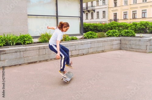Skater girl jumping kickflip in the street. Skateboarding trick outdoors.  photo