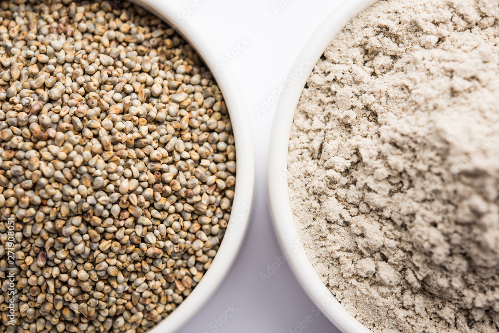 Bajra (pearl millet) / sorghum grains with it's flour or powder in a bowl, selective focus Bajra (pearl millet) / sorghum grains with it's flour or powder in a bowl, selective focus