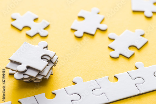 selective focus of connected jigsaw near stack of puzzle pieces on yellow