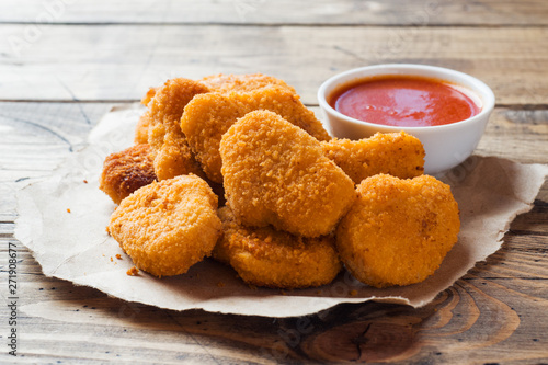 chicken nuggets with tomato sauce on wooden background. Copy space.