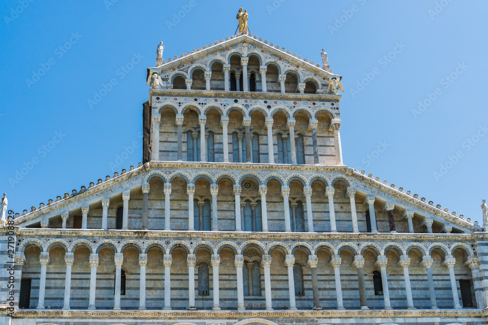 Details of the facade of the Medieval Roman Catholic Cathedral built in a Romanesque architectural style with multicolored marble, mosaic and high arches in the Piazza dei Miracoli, Pisa, Italy.
