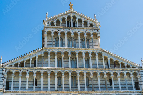 Details of the facade of the Medieval Roman Catholic Cathedral built in a Romanesque architectural style with multicolored marble, mosaic and high arches in the Piazza dei Miracoli, Pisa, Italy.