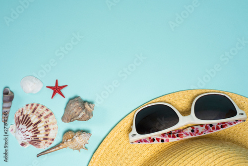 Seashells, hat and sunglasses on a blue background. Summer by the sea or ocean. Empty space for text