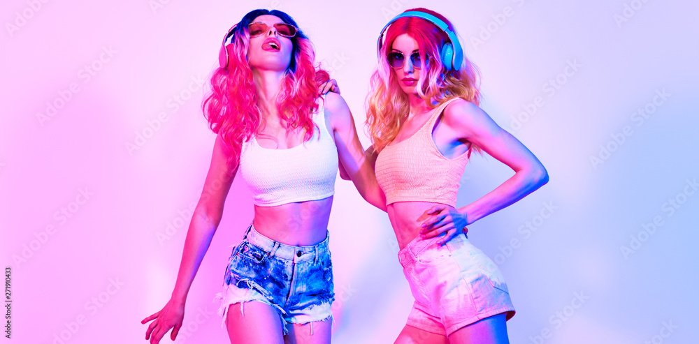 Fashion. Two DJ girl in Colorful neon light enjoy music, friends