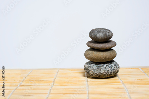 Stones stand on top of each other on a bamboo mat on a white background. Spa  relaxation  tranquility. Empty space for text