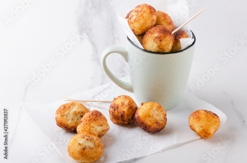 Cup full of fried sweet cheese balls on the baking paper.Sweet delicious snack photo