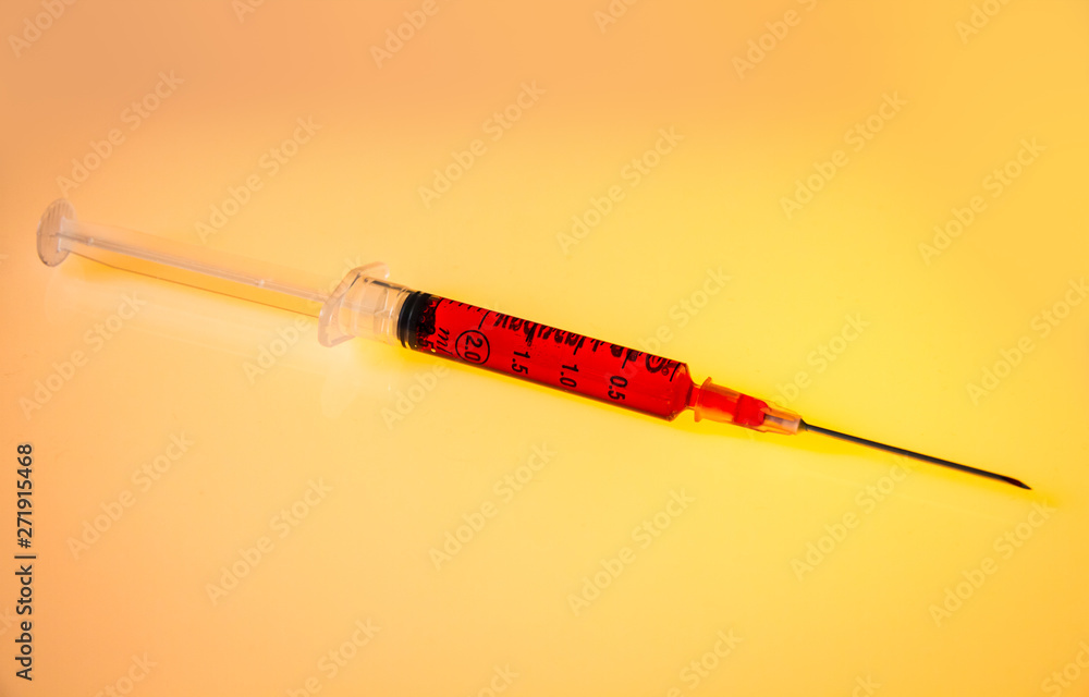 Fototapeta premium Syringe with blood on orange background