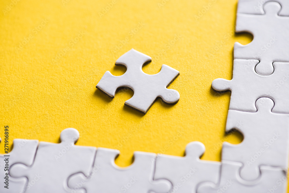 Obraz premium white puzzle piece near connected jigsaw on yellow