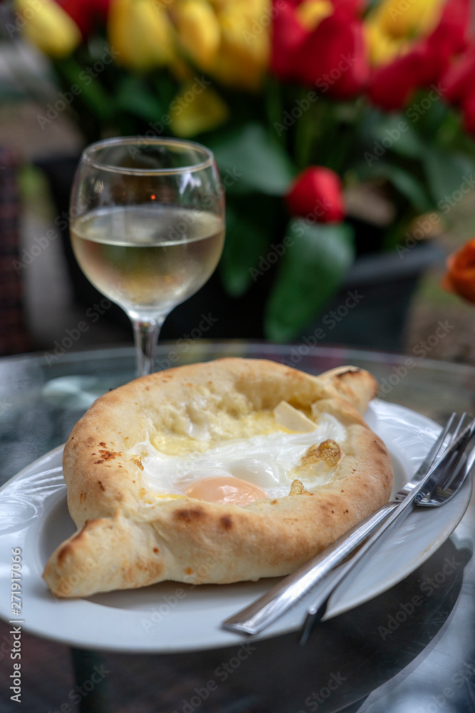 Adjarian khachapuri in restaurant. Open bread pie with cheese and egg yolk. Yummy georgian cuisine. Adjarian khachapuri in restaurant. Open bread pie with cheese and egg yolk. Yummy georgian cuisine.