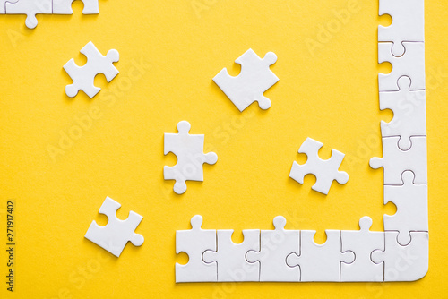 top view of incomplete connected puzzle pieces near finished line isolated on yellow
